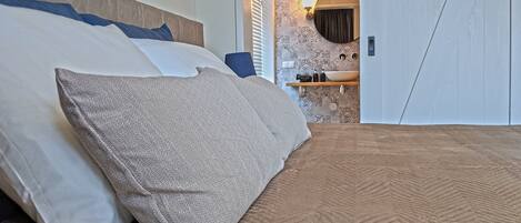 A bed with a textured brown cover and a grey pillow.