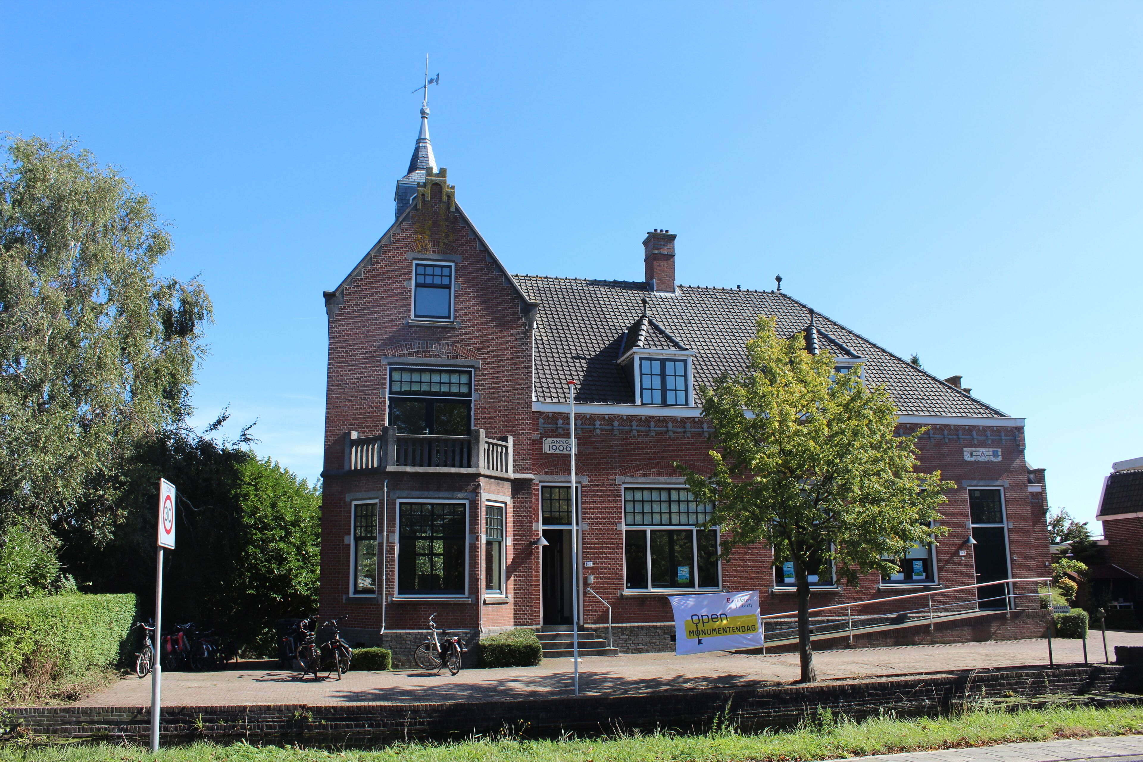 Een historisch bakstenen gebouw met een opvallende toren, grote ramen en een bord dat het een museum identificeert.
