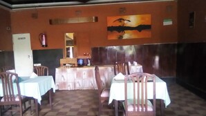 A restaurant with a checkered floor, wooden chairs, and tables covered with white tablecloths. - Sundowner Lodge (Nakuru)