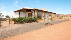 Une maison à l’extérieur blanc, avec des poutres en bois et une allée gravillonnée.