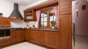 Une cuisine avec des meubles de rangement en bois, un réfrigérateur en acier inoxydable et une fenêtre avec des rideaux.