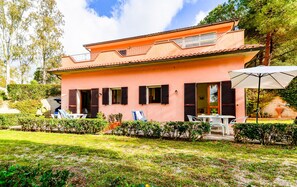 Une maison à deux étages avec un balcon, une terrasse dotée de mobilier d’extérieur et un jardin.