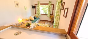 A room with a bed, a small table with a lamp, a window with curtains, and a wall with framed pictures. - Apartment in the countryside with garden - Apartment Wanna A (Capoliveri)