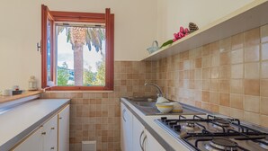 Eine kleine Küche mit Fenster, einem Gasherd und einem Spülbecken.