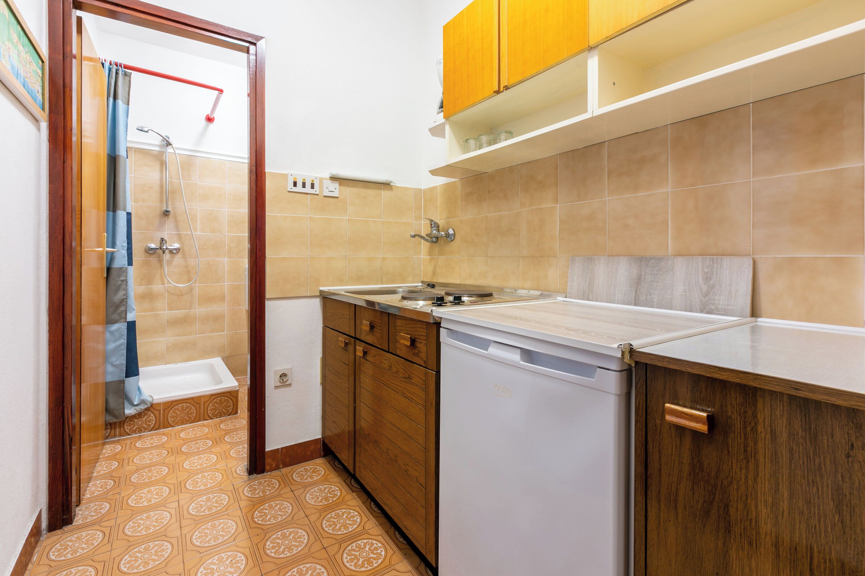 A compact kitchen with a sink, wooden cabinets, and a dishwasher.