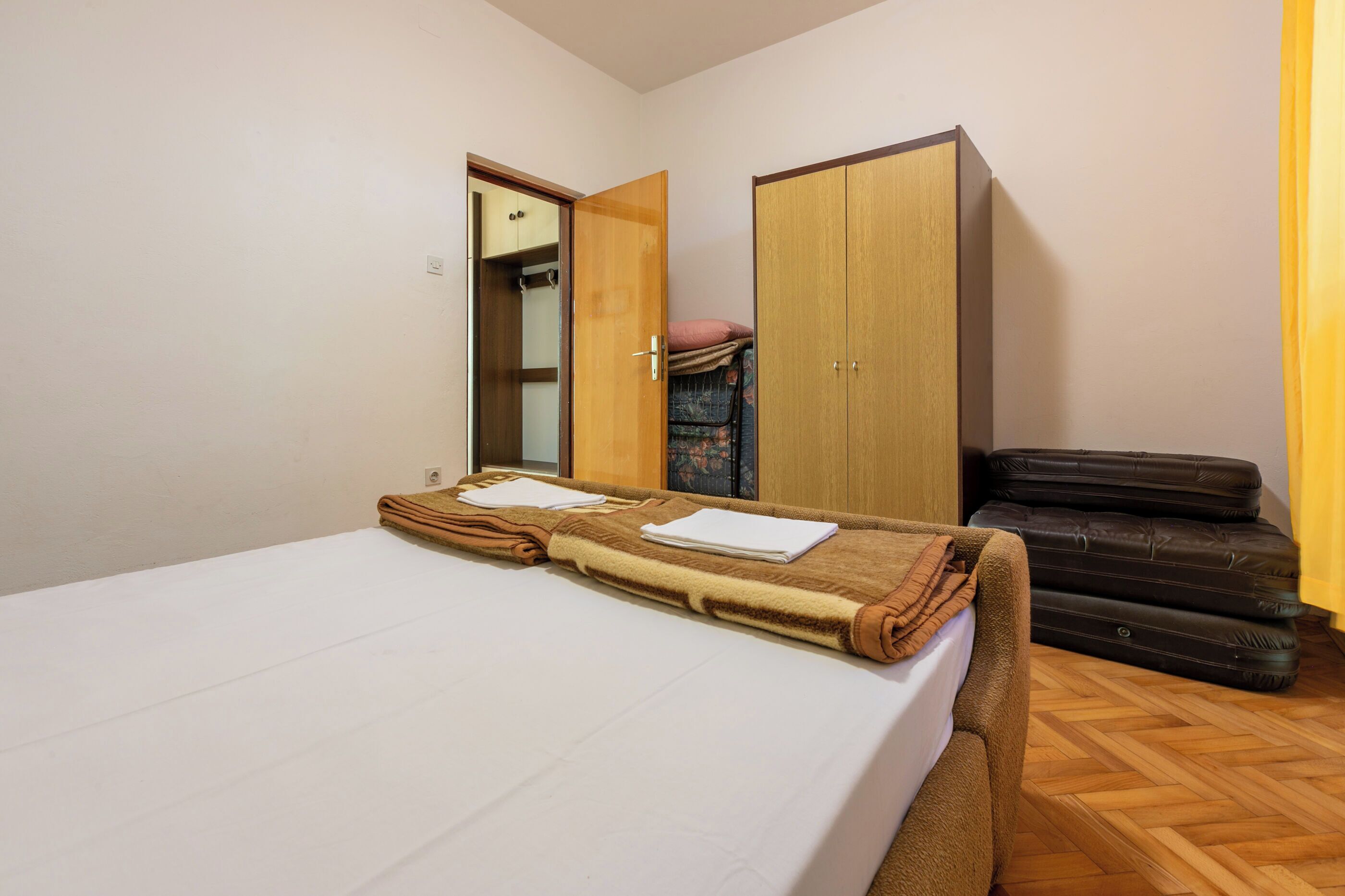 A bedroom with a bed, a wardrobe, and a suitcase.