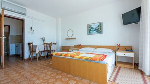 Ett hotellrum med en säng, ett skrivbord, en stol, en tv och en tavla på väggen.