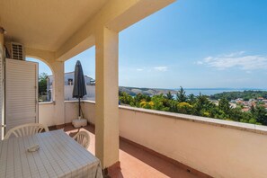 A balcony with a table, chairs, and an umbrella. - Apartments Sime (Lopar)