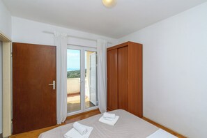 Un dormitorio con cama, armario y puerta corrediza de cristal que da a un balcón.