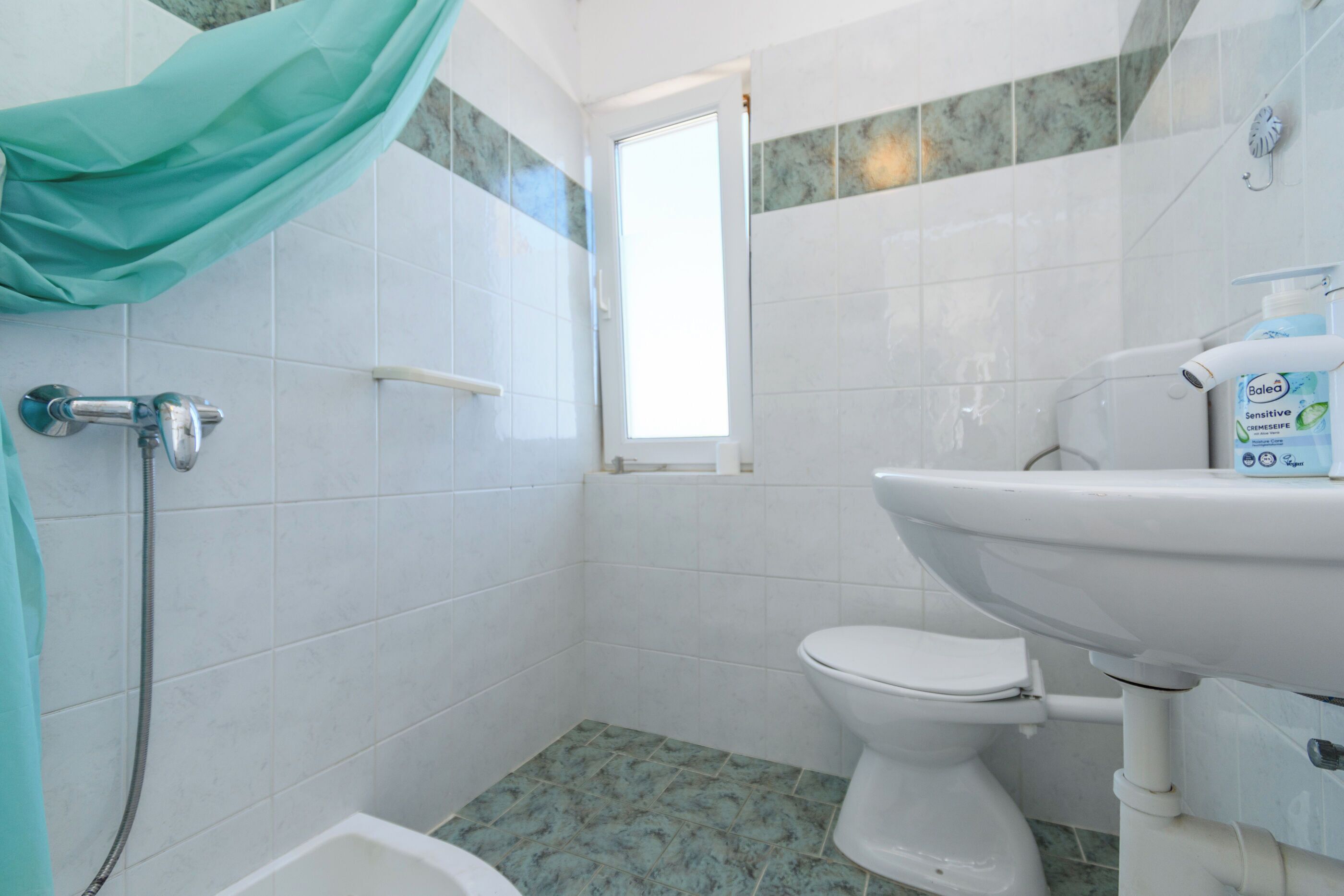 A bathroom with a shower, toilet, and sink.