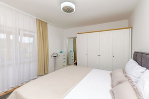 A bedroom with a bed, a wardrobe, a mirror, and a window with curtains. - Apartments Vinka (Sibenik)