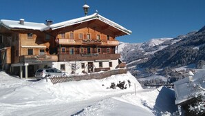 Un chalet en bois doté d’un balcon, entouré de montagnes enneigées.