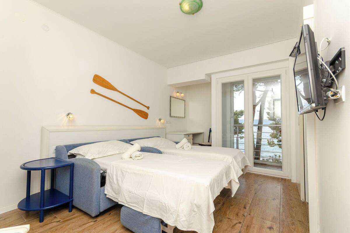 A bedroom with two beds, a small table, a mirror, and a TV.