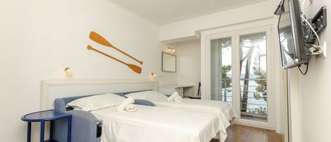 A bedroom with two beds, a small table, a mirror, and a TV.