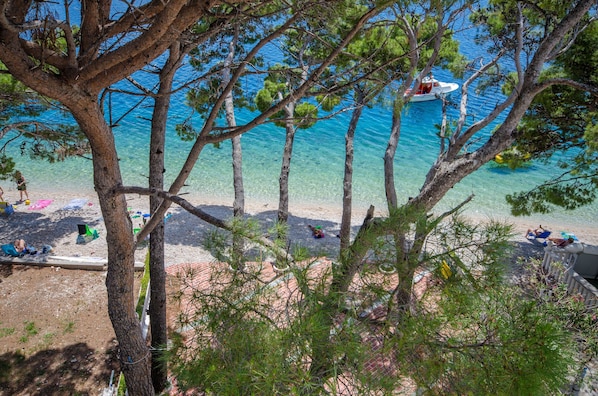 A beach with clear water, a boat, and people relaxing.