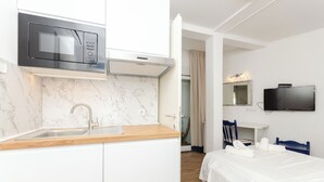 A modern hotel room with a kitchen area, a bed, a TV, and a bathroom. - Apartments Beach House Paradiso (Podgora)