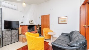 A living room with a fireplace, a television, a sofa, and a chair. - Apartments Beach House Paradiso (Podgora)