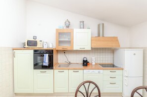 Una cocina compacta equipada con microondas, horno, cafetera y un refrigerador pequeño.