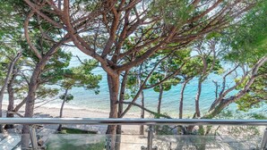A balcony with a view of a beach and trees. - Apartments Beach House Paradiso (Podgora)