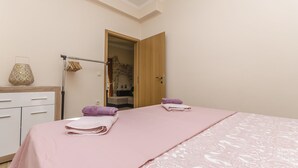 Une chambre à coucher avec un lit, une porte en bois, un porte-serviettes et une petite table avec une lampe.