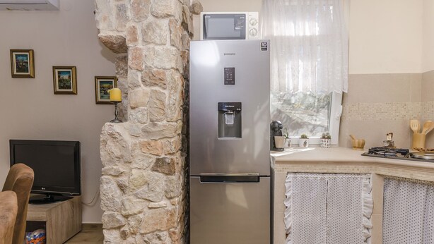 Une cuisine équipée d’un réfrigérateur en acier inoxydable, d’un four à micro-ondes et d’un mur en pierre.