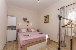 A bedroom with a bed, bedside table, wardrobe, and a window with curtains. - Apartment Mirella II (Tribunj)