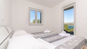 Et soveværelse med to senge, et vindue og en balkon med udsigt.