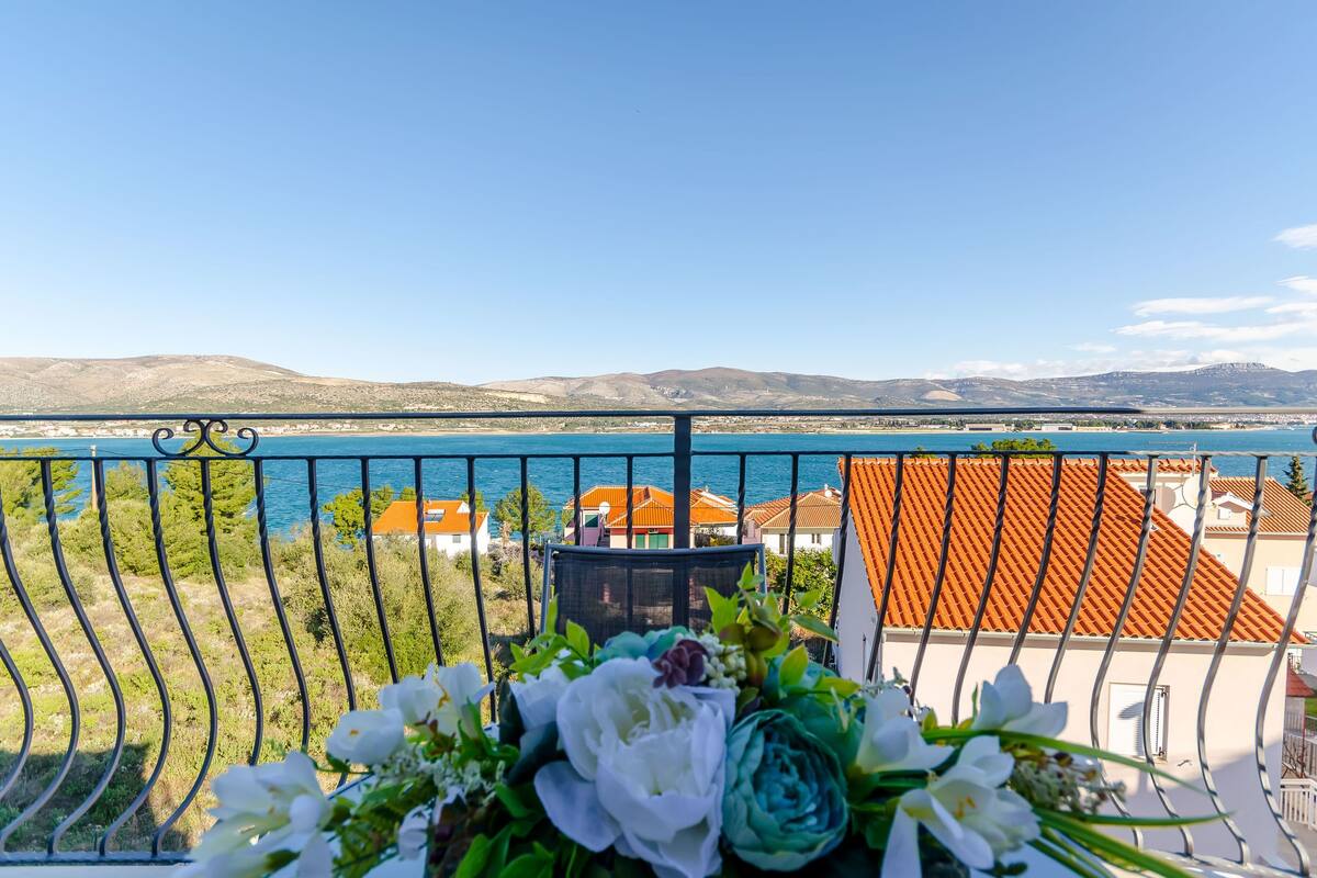 A balcony with a view of a body of water and distant mountains.