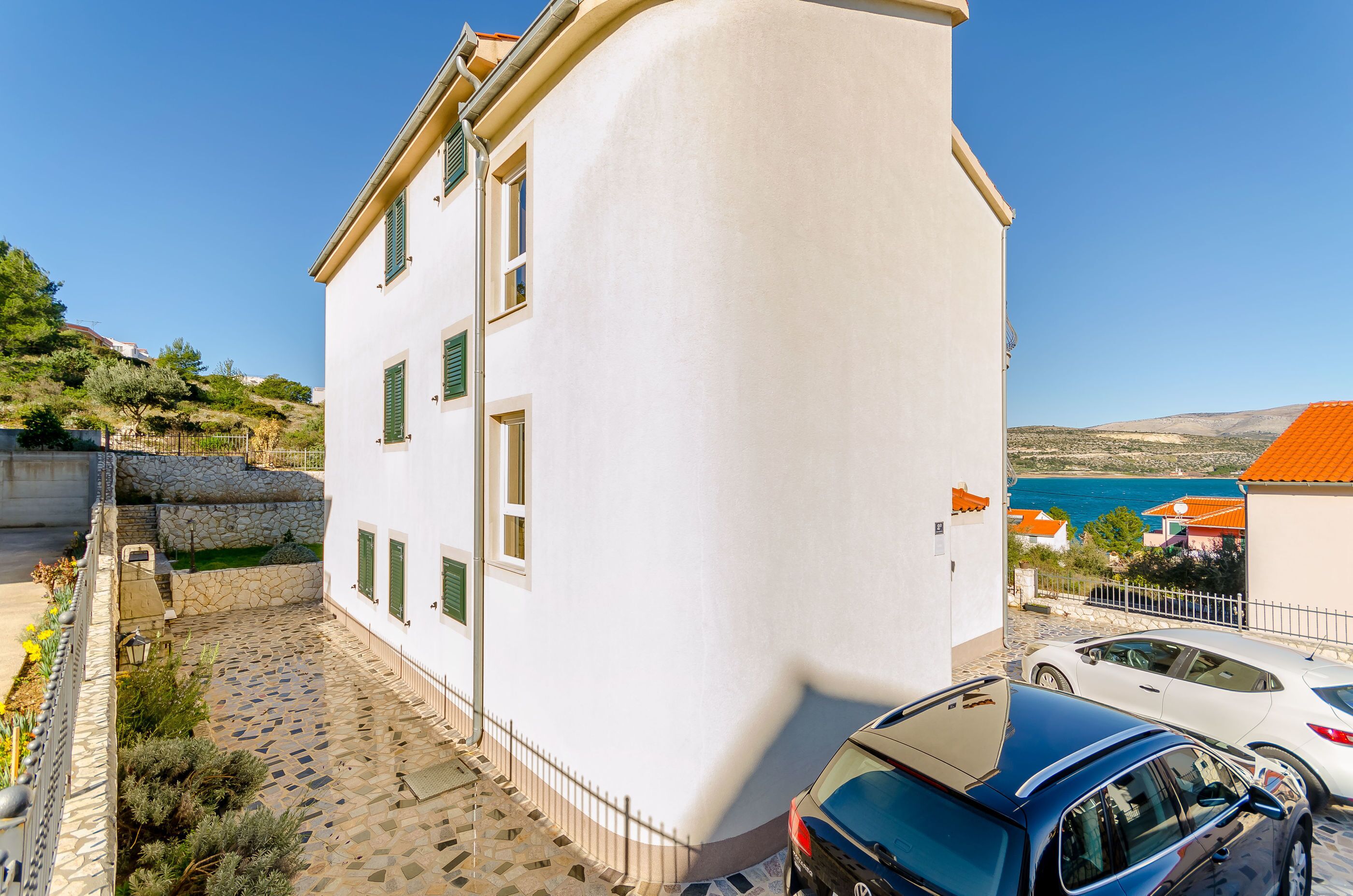 A white building with a stone staircase and a paved courtyard.