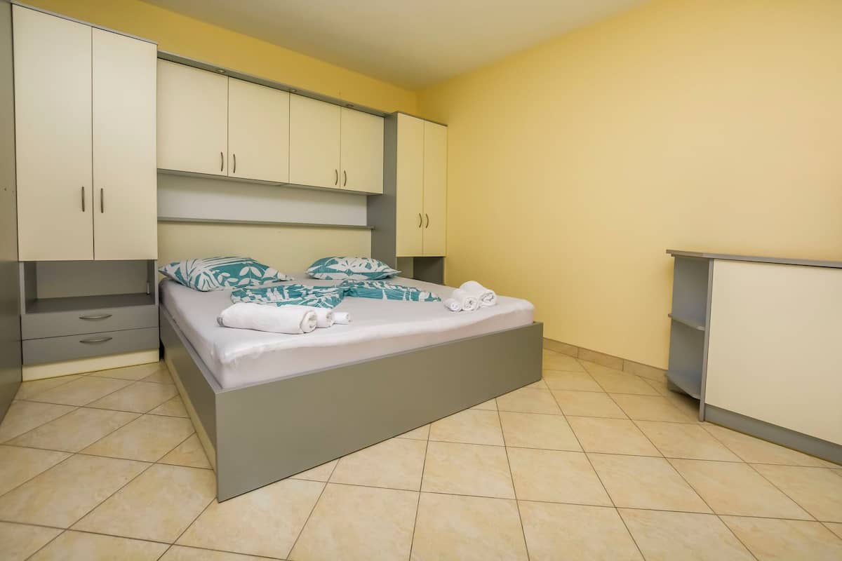 A bedroom with a bed, a wardrobe, and a small cabinet.