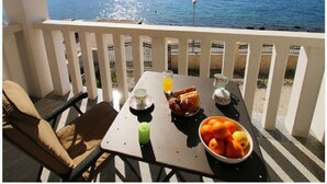 A balcony with a table set for breakfast, overlooking a body of water and a distant hill. - Apartments Villa J i M by the sea (Stupin Celine)