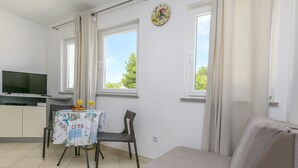 Une chambre avec une télévision, une table avec le petit-déjeuner, deux fenêtres et un canapé.