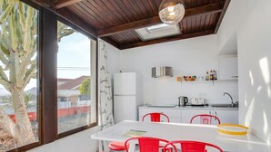 Uma cozinha moderna com armários brancos, bancada branca e cadeiras vermelhas.