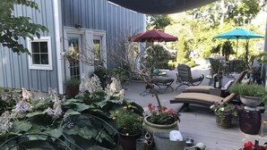 Eine Terrasse mit Gartenmöbeln, Blumentöpfen und Sonnenschirmen.