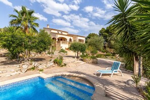 A pool with a blue border, a lounge chair, and a building with arches.