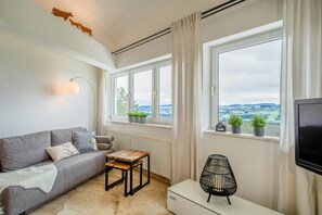 Ett modernt vardagsrum med en soffa, ett litet bord, en tv och ett fönster med utsikt.