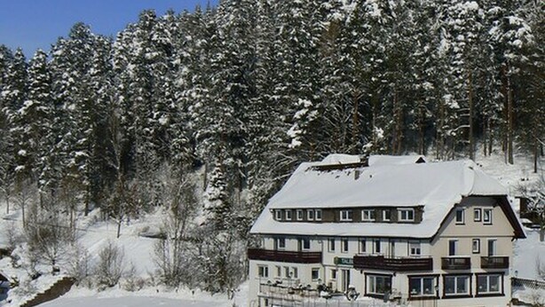 A multi-story hotel with a snow-covered roof and a balcony on the upper floor. - Pension Talblick (Baiersbronn)