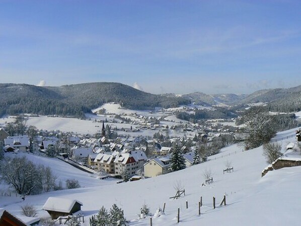 A snow-covered town with buildings and a church, surrounded by hills. - Pension Talblick (Baiersbronn)