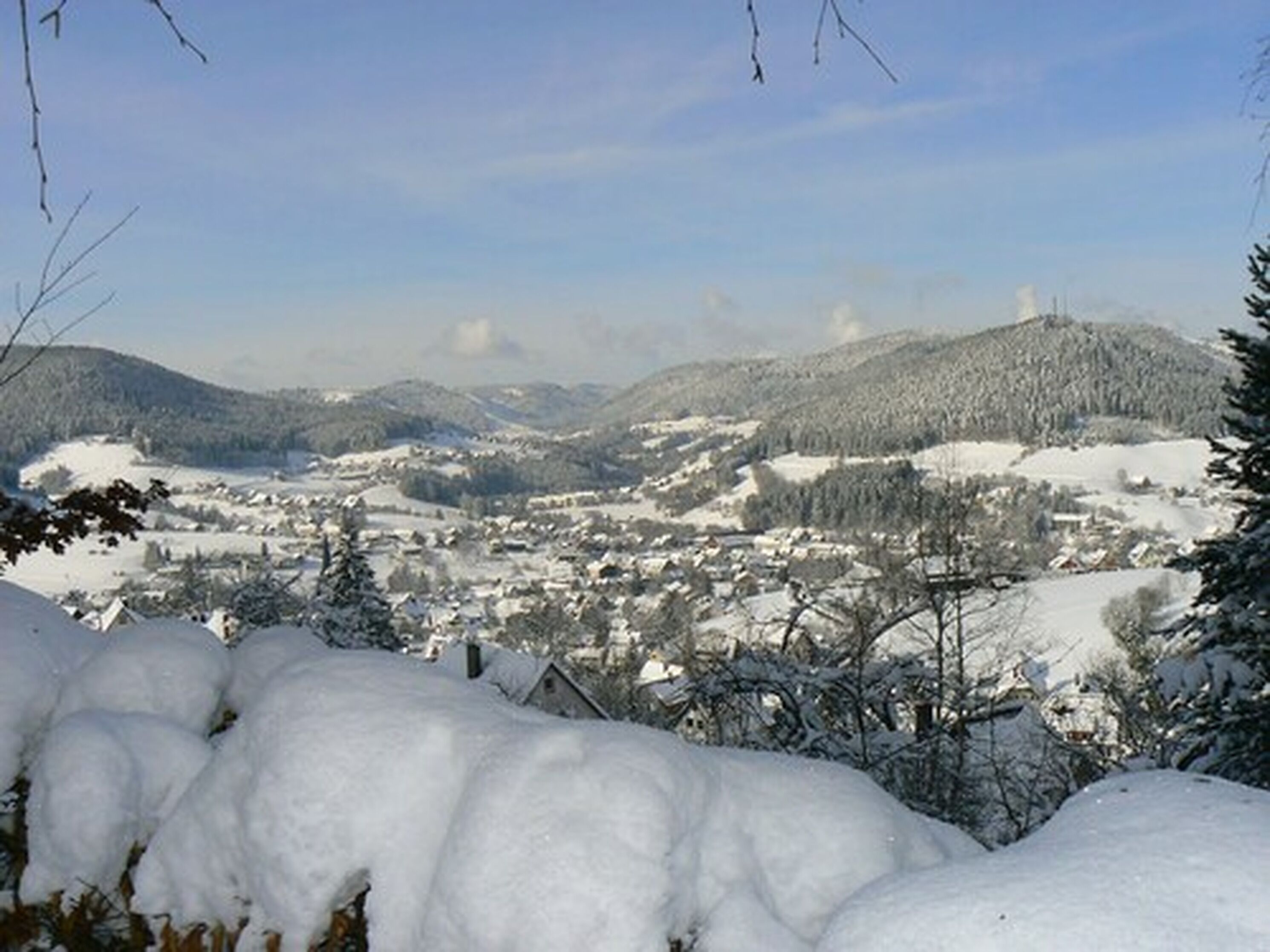 A snowy landscape with a town nestled in the valley, surrounded by hills.