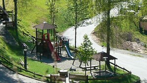 A playground with slides and a gazebo, surrounded by a fence and trees. - Pension Talblick (Baiersbronn)