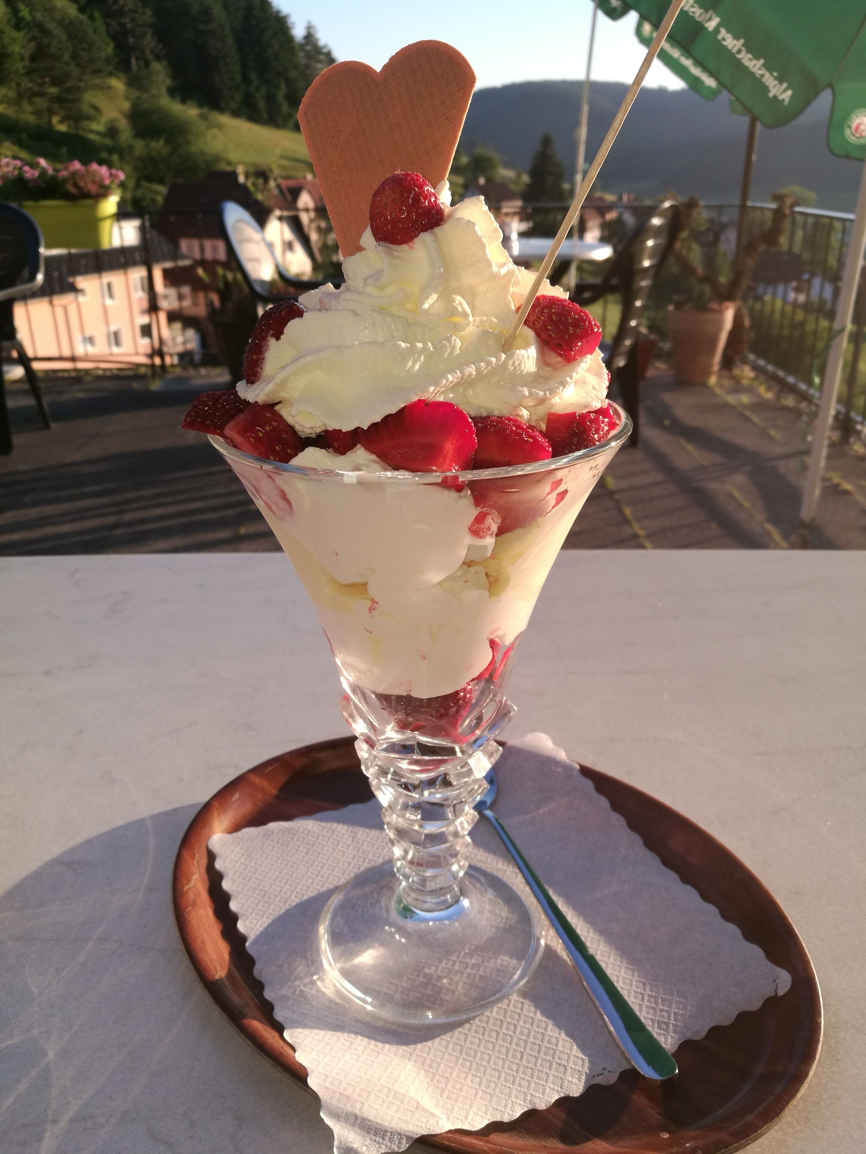 Un dessert servi dans un bol en verre, posé sur un plateau en bois.