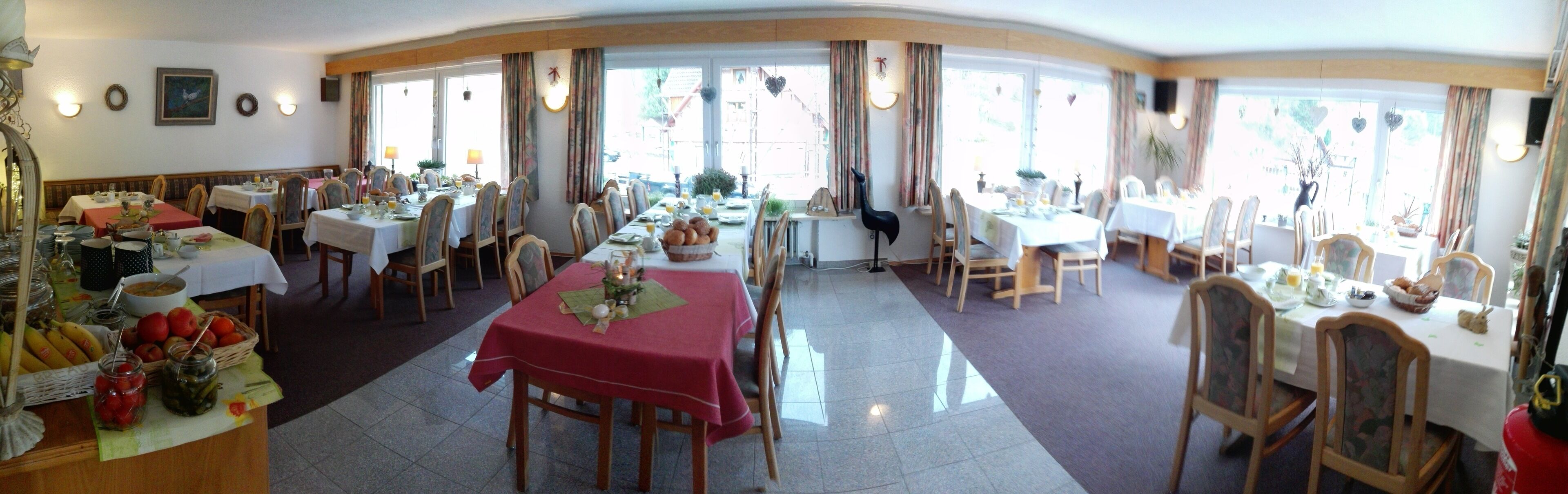 Un comedor con varias mesas, sillas y una variedad de alimentos a la vista.