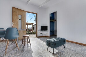 Ein Zimmer mit Fernseher, blauem Sessel, Holztür und einem gemusterten Boden.