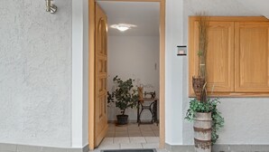 Een deuropening naar een kamer met een bloempot, een naaimachine en een houten kast.