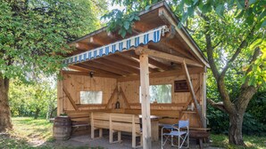 Een houten blokhut met een overdekte veranda, een bank, een stoel en een tafel.