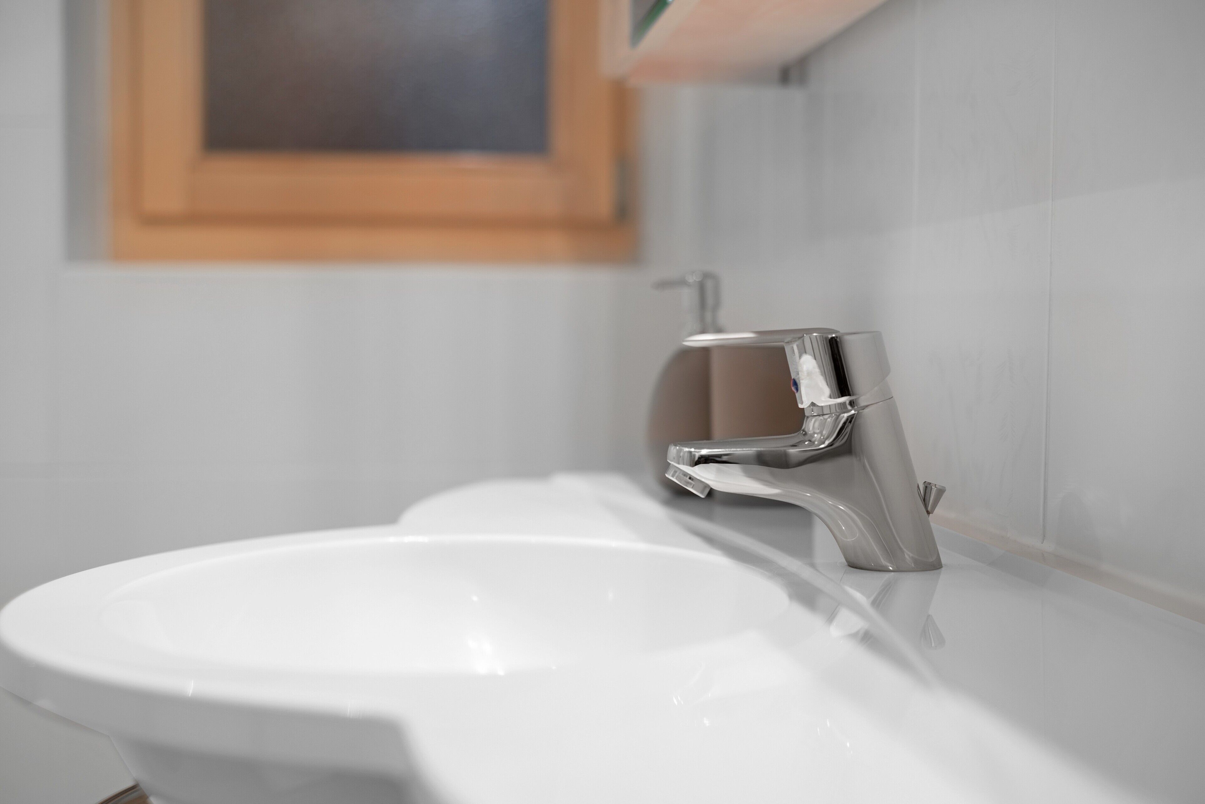 Un bagno con un lavandino bianco, un rubinetto cromato e un quadro appeso al muro.