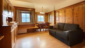 Een gezellig chalet binnen met houten wanden, een eethoek en een bank.