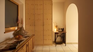 A room with a wooden wardrobe, a sewing machine, a table with a lamp, and a window with a view. - Holiday Apartment “Rafaser - Albina” with Mountain View & Wi-Fi (Feldthurns)