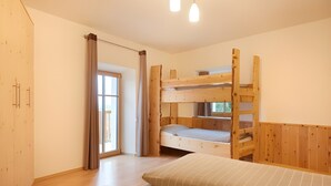 A room with a bunk bed, a single bed, a wardrobe, and a sliding door to a balcony. - Holiday Apartment “Rafaser - Albina” with Mountain View & Wi-Fi (Feldthurns)