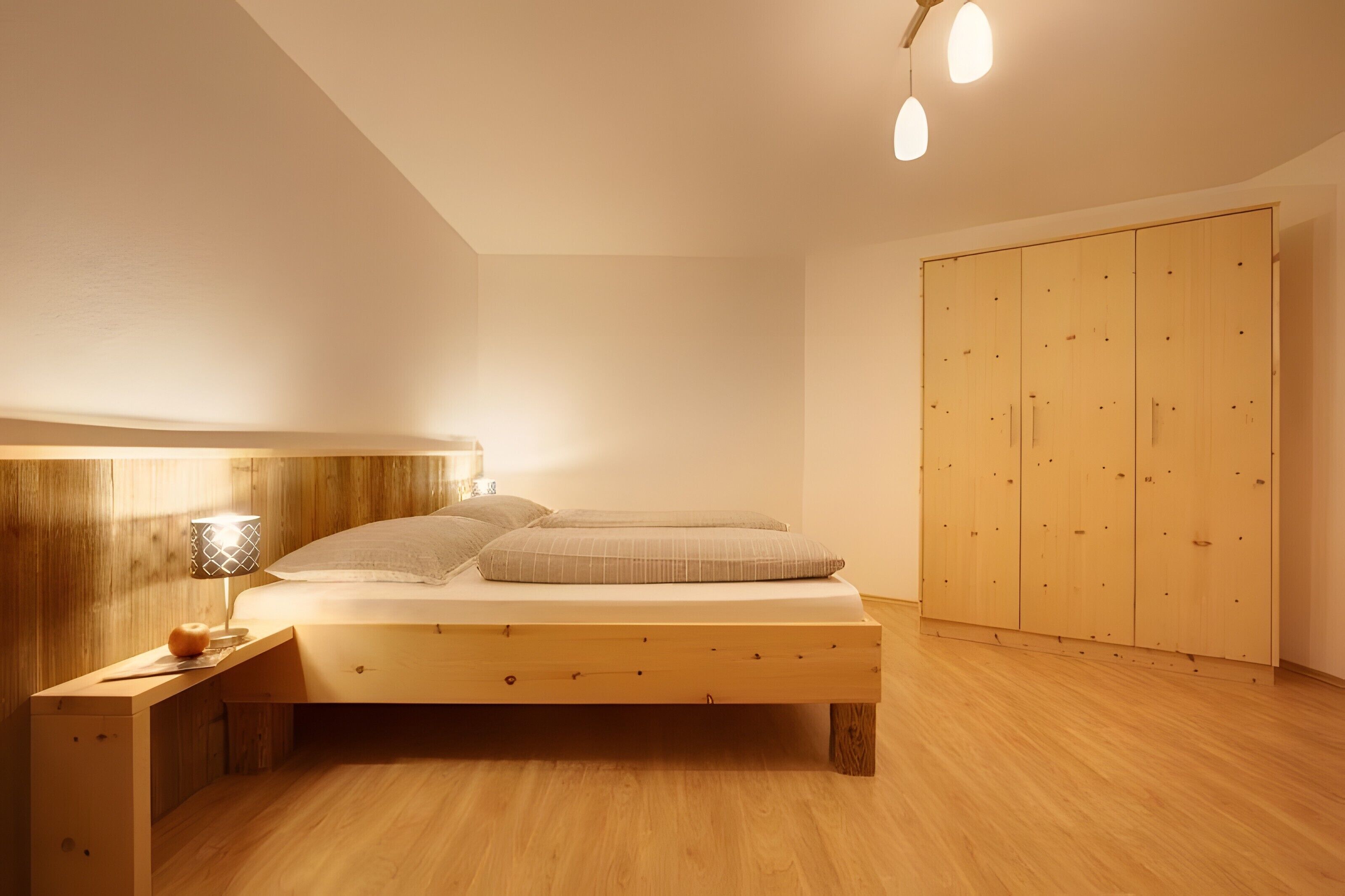 Ein Schlafzimmer mit einem Holzbett, einem Nachttisch mit Lampe und einem Kleiderschrank.